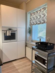 a kitchen with white cabinets and a stove and a window at Borg Kiertokatu, Spacious Studio Apt, Free Parking in Pori
