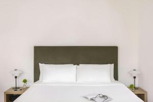 a bedroom with a white bed with two lamps at Numa Milan Montenero in Milan