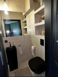 a bathroom with a black toilet and a mirror at S Golf Apartament in Gowinko +8 photos