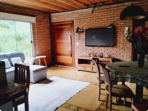 a living room with a tv and a brick wall at Casa Reserva da Gávea Visconde de Mauá in Visconde De Maua