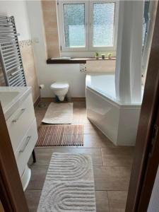 a bathroom with a bath tub and a toilet at Fewo Eifel Dahlem Nationalpark Sonnenterrasse & Kamin in Dahlem +21 photos