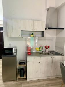 a kitchen with white cabinets and a sink and a microwave at Lemon Luxury Studio in Xanthi