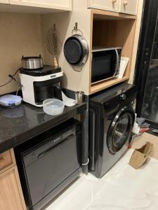 a kitchen with a washing machine and a microwave at Sumeru in Mumbai