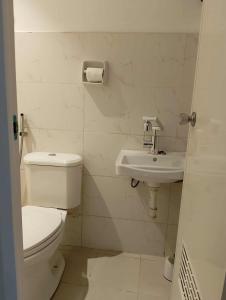 a white bathroom with a toilet and a sink at Modern 2 Storey 2BR Home with 2 Parking Space in Manila +8 photos