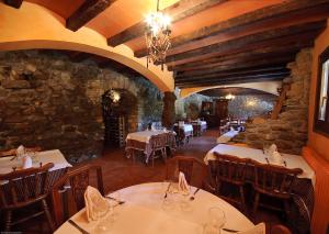 a restaurant with tables and chairs and a stone wall at Els Torrents in Bellver de Cerdanya