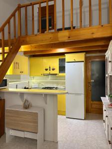 eine Küche mit gelben Schränken und einem weißen Kühlschrank in der Unterkunft Caelum in Riumar