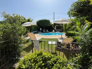 a swimming pool with two umbrellas and a fence at Chambres d'Hôtes et Gîtes Le Mas Mellou in Orange