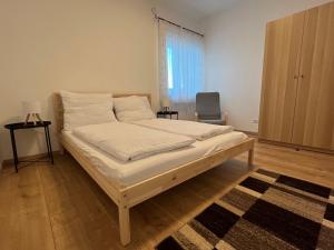 a bedroom with a bed with white sheets and a rug at Haus am Akazienweg in Steinberg an der Rabnitz