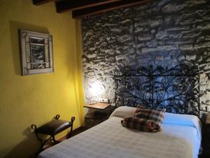 Un dormitorio con una cama y una pared de piedra. en Els Torrents, en Bellver de Cerdanya 