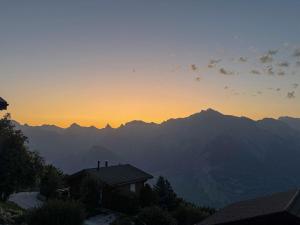 a sunset over the mountains with a house in the foreground at Chalet La Balance by Interhome in Nendaz +57 photos