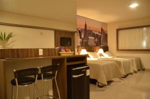um quarto de hotel com uma cama e um bar com cadeiras em Hotel HortoPlaza em Hortolândia