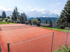 a tennis court with mountains in the background at Apartment Regina D1 by Interhome in Arveyes