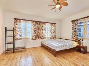a bedroom with a bed and a fan and windows at Villa Švýcarka by Interhome in Mladé Buky