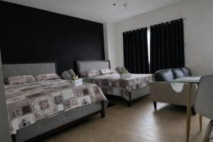 a bedroom with two beds and a chair and a window at J & F Homestay - Cavite, Philippines in Trece Martires +1 photo
