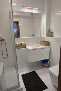 a white bathroom with a sink and a shower at Bootanica Apartament Piła in Piła