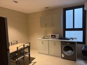 a small kitchen with a washing machine and a table at Milano Hotel in Al-ʿUla