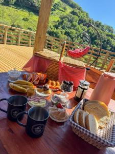 a table topped with baskets of bread and fruit at Chalé Rio Capetinga 01 in Anchieta +15 photos
