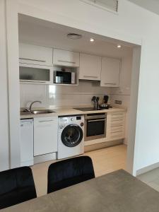 a kitchen with white cabinets and a washing machine at Albir Beach & Sea Apt in Albir