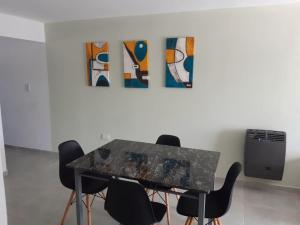 a table and chairs in a room with a painting at Traslasierra Champaquí Deptos in Villa Dolores