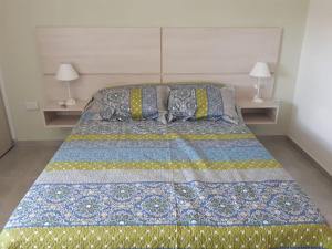 a bed with a blue and yellow quilt and two lamps at Traslasierra Champaquí Deptos in Villa Dolores