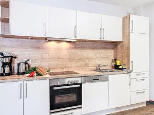 a kitchen with white cabinets and a stove top oven at Apartment Alpenlodge Breitenberg by Interhome in Lechbruck
