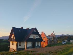 a house with a black roof on a hill at Pokoje u Jozka-Widok na Tatry in Groń