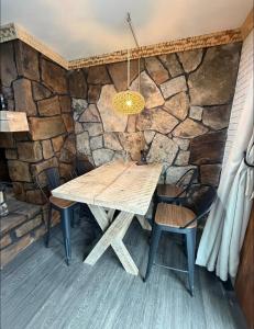 a wooden table and chairs in front of a stone wall at cozy cabin in Dalton