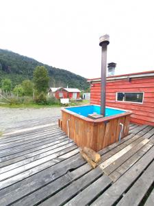 a hot tub on a deck next to a building at Cabaña Hornohuinco in Llanquihue