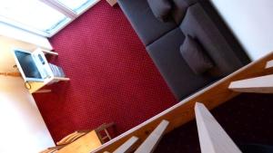 Habitación con pared roja y escalera con TV. en Ferienwohnung Grischuna en Bivio