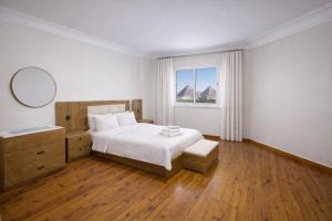 a white bedroom with a bed and a window at 3 Pyramids Grand Egyptian Museum View in Cairo