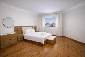 a white bedroom with a bed and a window at 3 Pyramids Grand Egyptian Museum View in Cairo