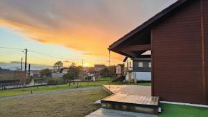 a house with a wooden deck with a sunset in the background at Vencello Estelar Compostela in Santiago de Compostela