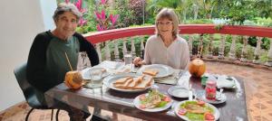 a man and woman sitting at a table with food at Nobel Bibila Hotel in Bibile