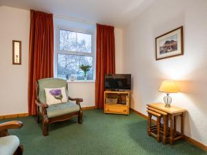 a living room with a chair and a television at Apartment Old Stable on Aigas Golf Course by Interhome in Beauly