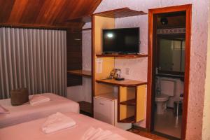 a small room with two beds and a television at Resort Pedra do Sonho in Janaúba