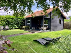 a small house in a yard with a lawn sidx sidx sidx at Landelijk gelegen houten huisje in Opperdoes