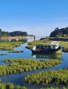 a boat on the water with a lighthouse in the background at chambres randonneurs in Plestin-les-Grèves