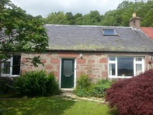 a red brick house with a green door at Smithy Cottage in Blairgowrie