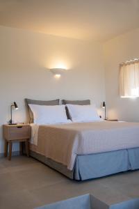 a bedroom with a large bed and a night stand at Alma Sunset Suites in Ios Chora +49 photos