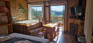 a bedroom with a tub and a balcony with a view at Pousada Chales Rancho Caipira in Santo Antônio do Pinhal