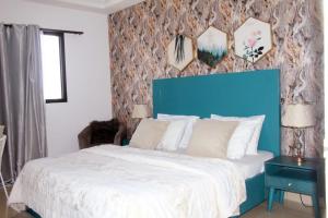 a bedroom with a large bed with a blue headboard at AZURA Skyline in Abidjan