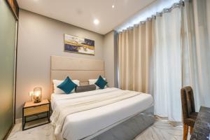 a bedroom with a large white bed with blue pillows at Hotel Velvet Dreams Inn & Banquet in Kharar