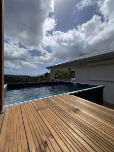 a swimming pool with a wooden deck next to a house at Villa Altura in Rivière-Salée