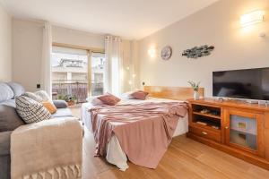 a bedroom with a bed and a couch and a tv at Terraza con encanto Parking Piscina Portaventura in Salou
