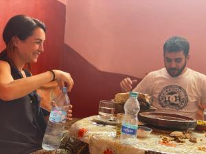 a man and a woman sitting at a table with water bottles at Atlas House in Amizmiz