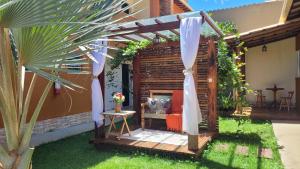 a backyard retreat with a pergola and a chair at Pousada Flor do Campo in Serra do Cipo