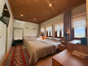 a bedroom with two beds and a tv and windows at The Stone Sky Hotel in Gjirokastër