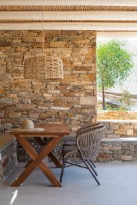 a wooden table and chair in front of a brick wall at Alma Sunset Suites in Ios Chora