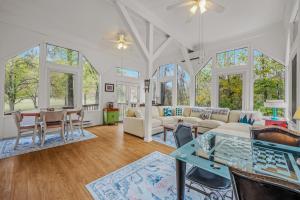 a living room with white furniture and windows at River Time Cabin - Riverfront, Hot Tub, Screen Porch, Fishing, Games, View, 3 King Beds in Berkeley Springs