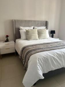 a bedroom with a large bed with white sheets and pillows at Moonlight Apartment in Gaborone +5 photos